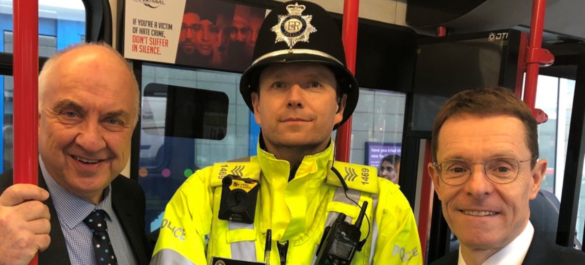 Mayor standing with another man and police officer smiling on the tram