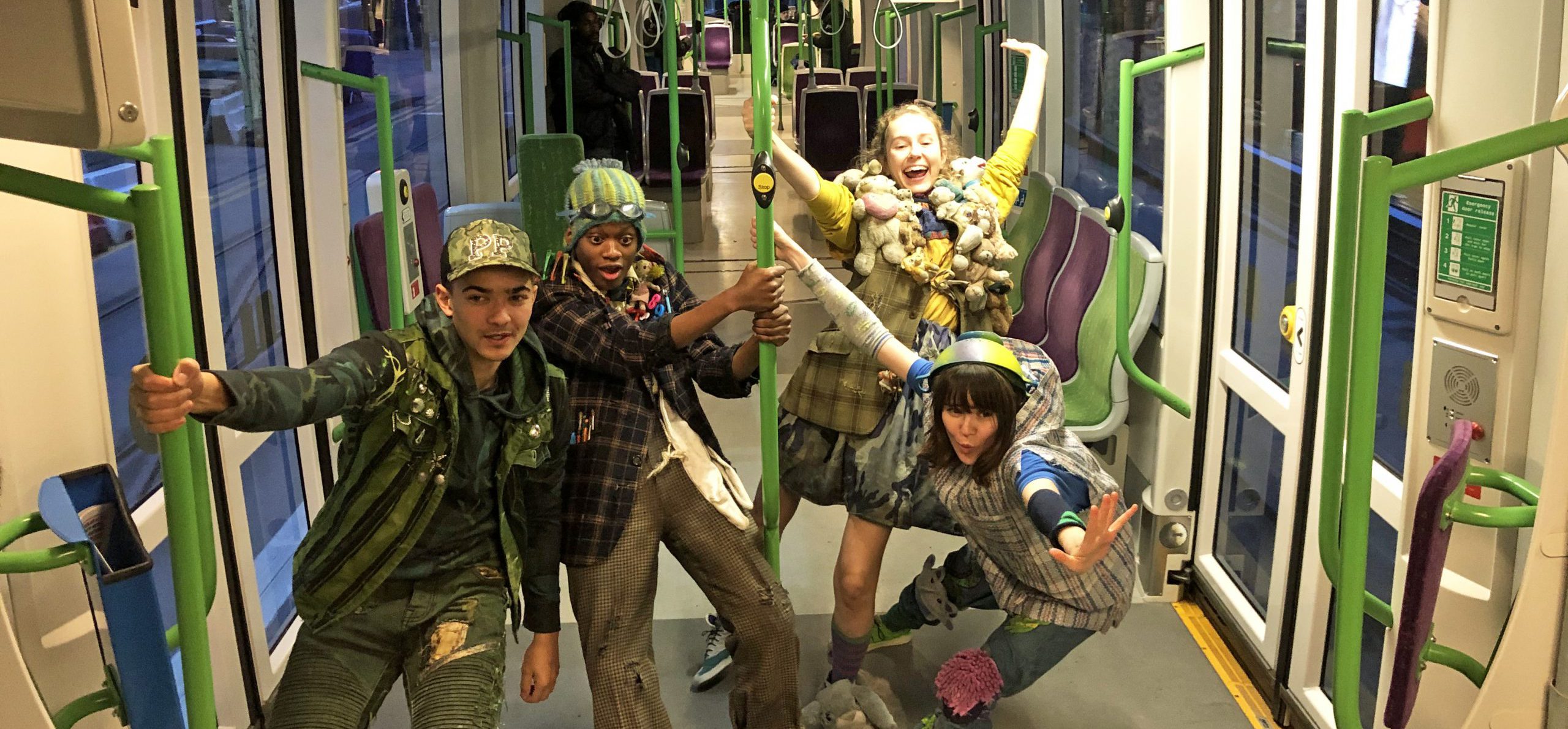 Four young people dressed in Peter Pan costumes posing on the tram