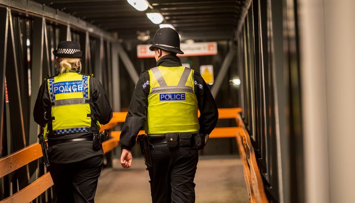 Woman and man police officers walking through tram stop at night