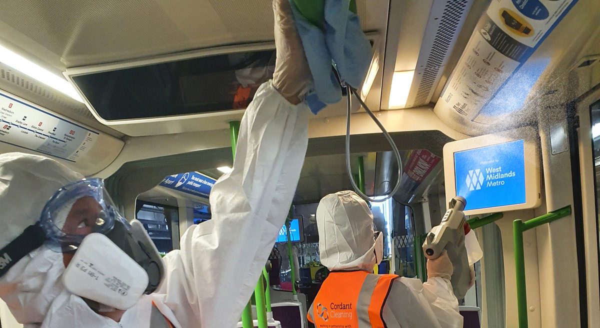 Cleaning crew in sterilised suits and face masks cleaning inside of tram for COVID regulations