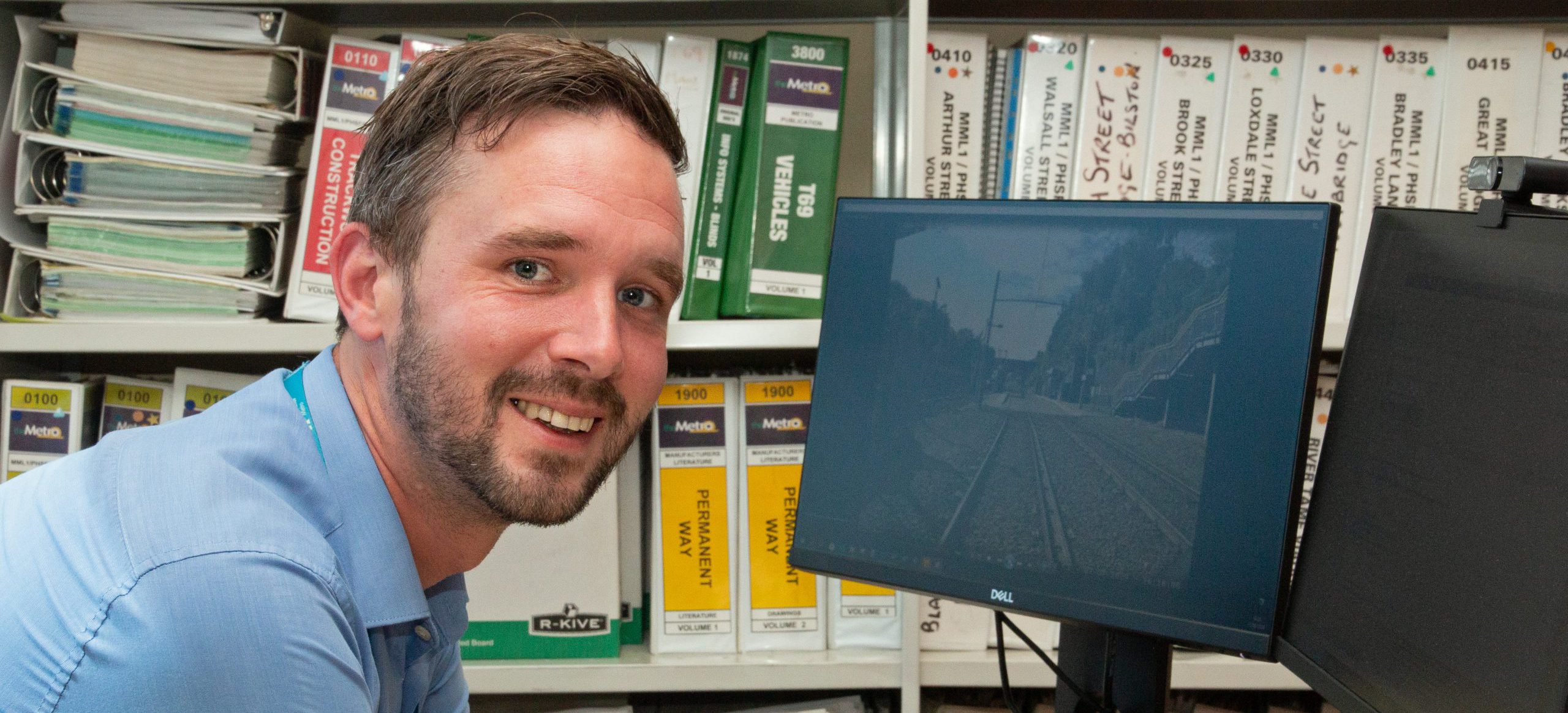 Man in office at computer smiling at camera