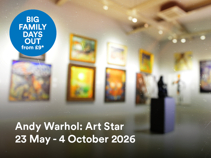 Blurred image of an art gallery. With white walls and framed pictures hung on the wall. A sculpture can be seen in the centre of the room.
